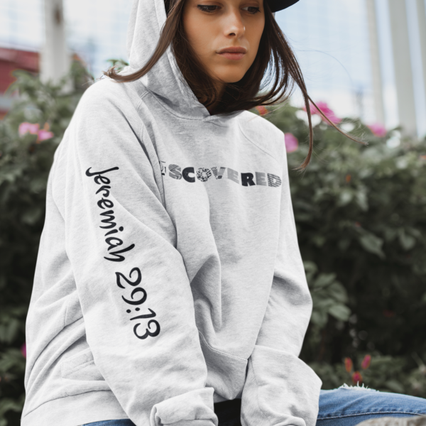 Young Lady wearing a gray and white hoodie with Jeremiah. 29:13 bible scripture on right sleeve